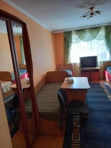 ein Hotelzimmer mit einem Bett, einem Tisch und einem TV in der Unterkunft Готель Поділля in Shestakovka