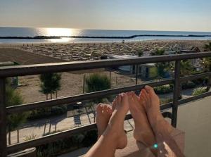 une personne assise sur un balcon donnant sur la plage dans l'établissement Hotel Ridens, à Rimini