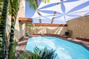 a swimming pool with an umbrella next to a building at פאטה מורגנה אואזיס - בית נופש פרטי עם בריכה מחוממת in Beer Sheva