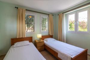 two beds in a bedroom with two windows at Korsan Apartment No.16 in Kaş