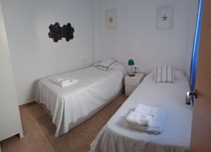 two beds in a room with white walls at Geranio Chipionahome in Chipiona +44 photos