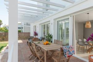 un patio con una mesa de madera y sillas en un porche en Villa Girasol en Benalup Casas Viejas