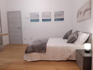 a white bedroom with a bed and paintings on the wall at Piazza Mazzini Apartment in Lecce