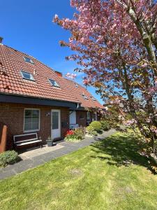 a brick house with a bench and a tree at Nordseetraum - Ferienhaus Wolke in Friedrichskoog