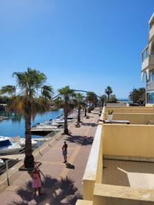 deux personnes marchant sur un trottoir à côté d'une marina dans l'établissement Grand T2 proche de la mer, à Sète