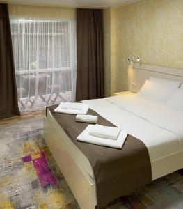 a bedroom with a large bed with two towels on it at Hotel Sonata in Batumi