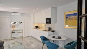 a kitchen with a table and blue chairs in a room at Aldea Blanca Cute in Marbella