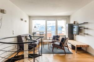 a living room with a table and chairs and a television at Apartment Alpenrose 2.5 mit Mitbenutzung SPA & Wellness - GRIWA RENT AG in Beatenberg
