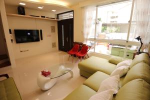 a living room with a couch and red chairs at Taitung Nine Three B&B in Taitung City