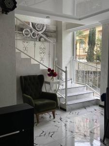 een woonkamer met een stoel en een trap bij Hotel Sonata in Batoemi