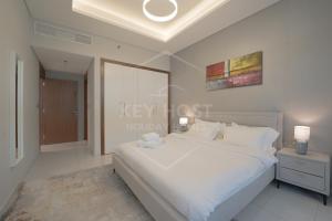 a bedroom with a white bed and a painting on the wall at KeyHost - Regent Court JVC - KG20 in Dubai