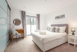 a white bedroom with a white bed and a chair at Luxury Apartment with Balcony, Free Parking in St Andrews
