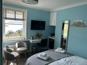 a blue bedroom with a bed and chairs and a desk at Castle View in Lochaline