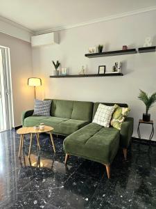 a living room with a green couch and a table at Modern Garden View Apt in Voula, Athens - Luxe in Athens