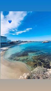 une plage avec un cerf-volant au-dessus de l'eau dans l'établissement Appart calme & chaleureux en résidence près de la mer, à Monastir