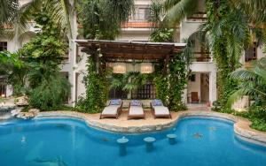 a hotel with a swimming pool and two lounge chairs at Hotel Hulku in Playa del Carmen