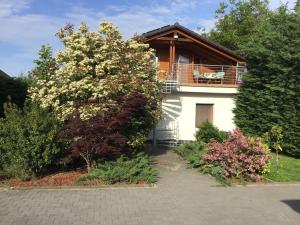a house with a balcony and some bushes at Drávecz Apartman in Balatonlelle