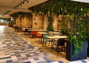 un restaurante con mesas, sillas y plantas en Amazonia Apartments en Timisoara