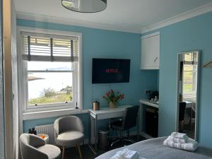 a blue room with a bed and a desk and a window at Castle View in Lochaline