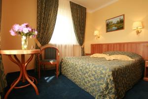 una habitación de hotel con una cama y una mesa con un jarrón de flores en Park hotel Ershovo, en Zvenigorod