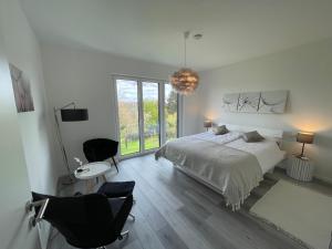 ein weißes Schlafzimmer mit einem Bett, einem Tisch und Stühlen in der Unterkunft Apartment mit Stil in Stuttgart
