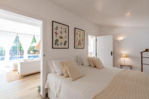 a white bedroom with a large bed with white pillows at Sete Quintas Country House in Salvaterra de Magos
