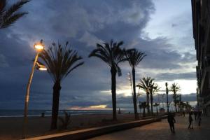 a street light next to a beach with palm trees at New Apartment 800m from the beach + pool + garage in Calafell