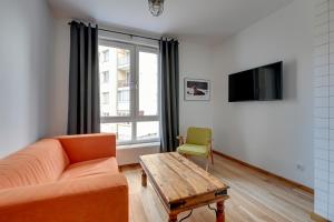 a living room with a couch and a table and a tv at Staywin WILCZA apartments in Gdańsk