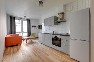 a kitchen with a refrigerator and an orange chair at Staywin WILCZA apartments in Gdańsk