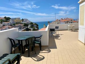 uma varanda com mesas e cadeiras e o oceano em Studio Calisto em Carvoeiro