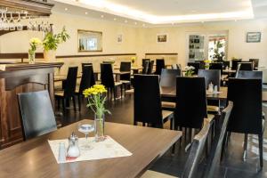 a restaurant with wooden tables and black chairs at Waldhotel am Aschergraben in Geising