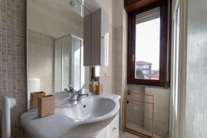 a white bathroom with a sink and a mirror at Parma Parco Ducale Duplex Apartment with parking in Parma