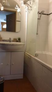 een badkamer met een wastafel, een bad en een spiegel bij mini villa 72, résidence avec piscine. in Serra-di-Ferro