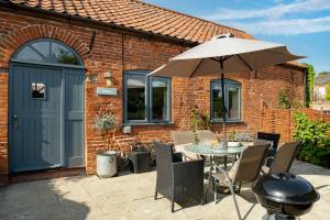 a patio with a table with an umbrella and chairs at The Stables in Tunstead