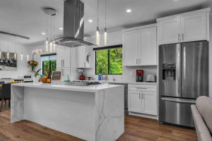 uma cozinha com armários brancos e um frigorífico de aço inoxidável em Glen Oak Bungalow em Los Angeles