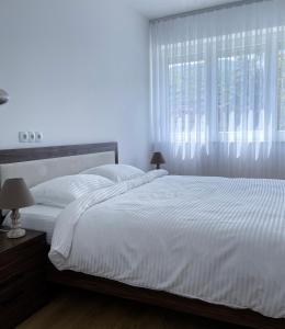 a bedroom with a large white bed with a window at Fellas Apartments in Prizren