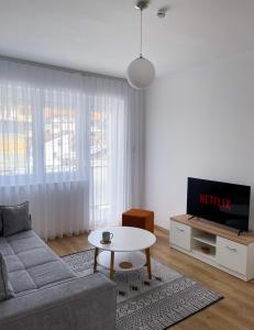 a living room with a couch and a table and a tv at Fellas Apartments in Prizren
