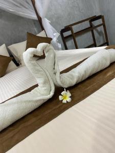 ein Bett mit Handtüchern drauf mit einer Blume drauf in der Unterkunft Shek villa in Hikkaduwa