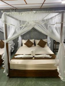 a bedroom with a canopy bed with white drapes at Shek villa in Hikkaduwa