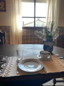 uma mesa com um prato e um copo e um vaso com flores em Casa do Conde Praia da Barra em Gafanha da Nazaré