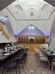 uma sala de jantar com mesas e cadeiras e uma igreja em Feruzkhan Hotel - Madrassah Mohammed Rakhim Khan 1871 em Khiva