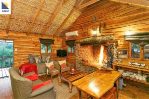 a living room with a fireplace in a log cabin at Riverside Guest Lodge in Oudtshoorn