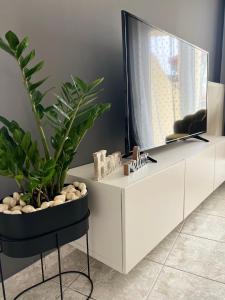 a white entertainment center with a tv and plants on it at KND Living Concept - Apartment in Heraklio Town