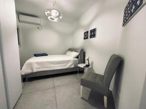 a small bedroom with a bed and a chair at Luxury 3 Rooms Apartament - NearTheSea Bat Yam in Bat Yam