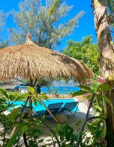 a resort with a straw hut and a swimming pool at 7SEAS Cottages in Gili Air