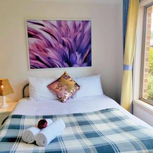 a bedroom with a bed with towels and a painting at Parliament Triangle * Garden View in Yarralumla
