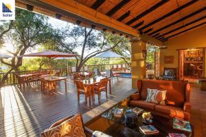 a patio with tables and chairs on a deck at Riverside Guest Lodge in Oudtshoorn