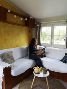 a woman sitting on a couch in a living room at La Parenthèse in Guénin