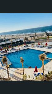 una gran piscina junto a una playa con palmeras en Porto Said Tourist Resort, en Puerto Saíd