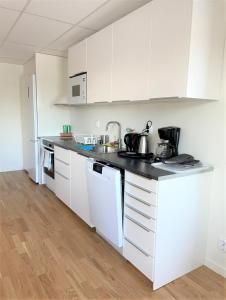 a kitchen with white cabinets and a black counter top at Rentalux Hostel in Timrå